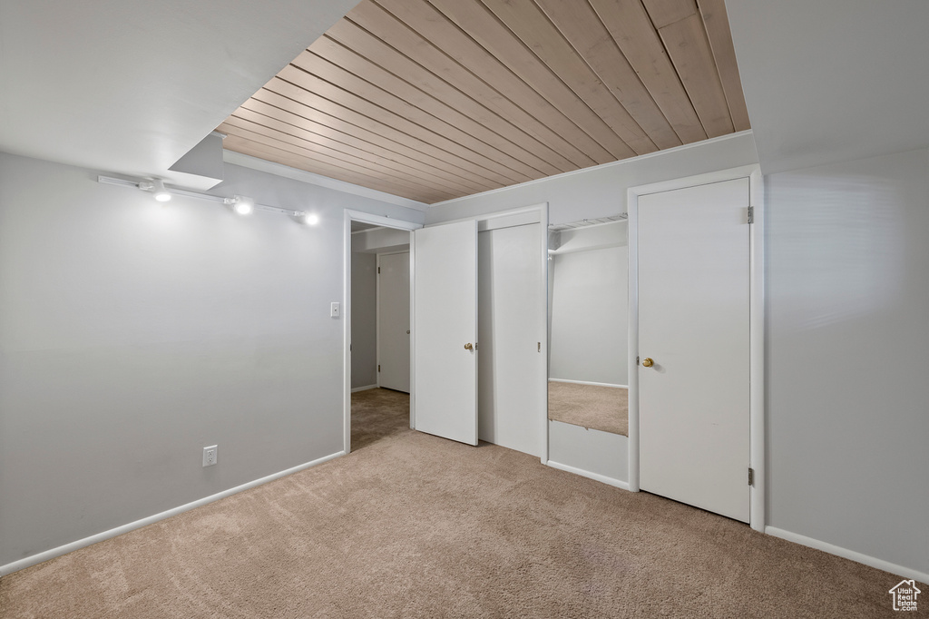 Unfurnished bedroom with light colored carpet, a closet, and wooden ceiling