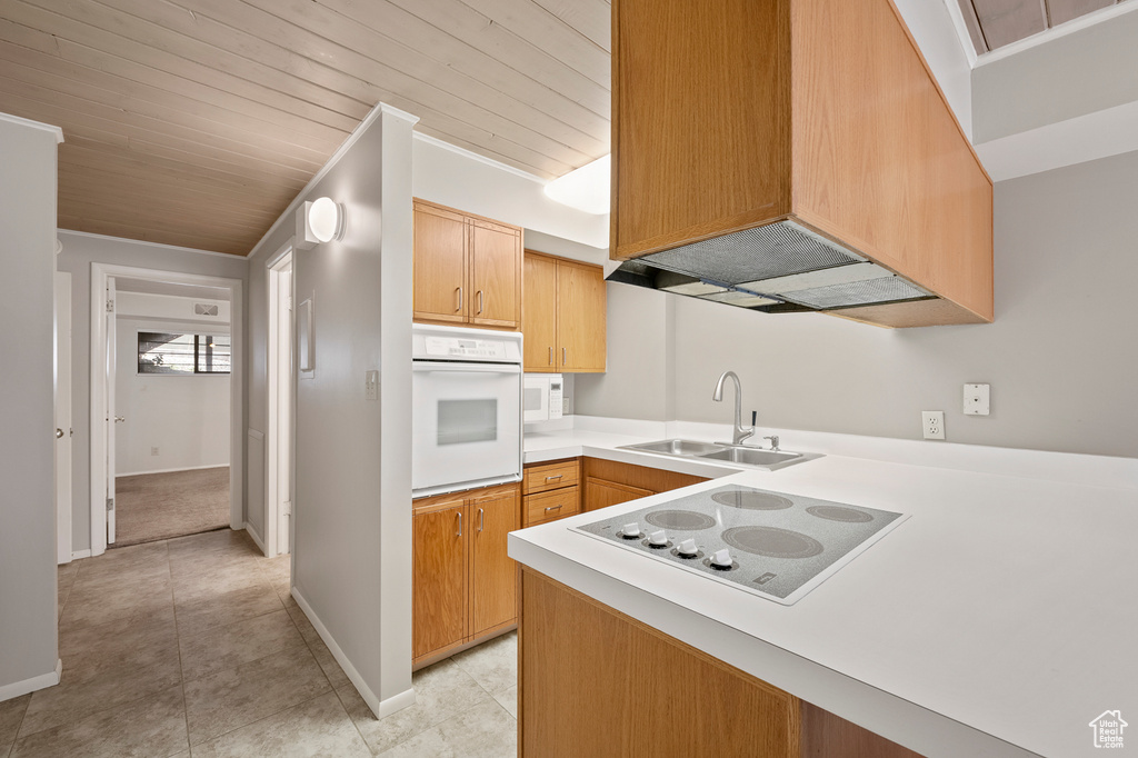 Kitchen with sink, white appliances, kitchen peninsula, and light tile flooring
