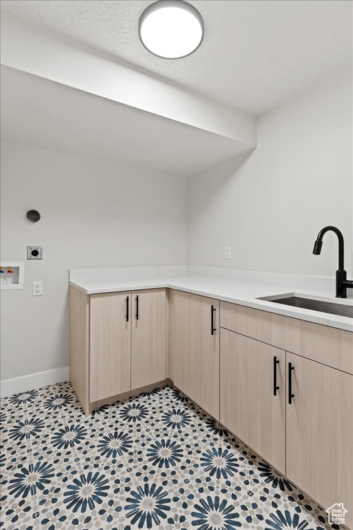 Interior space with sink, electric dryer hookup, cabinets, and light tile floors