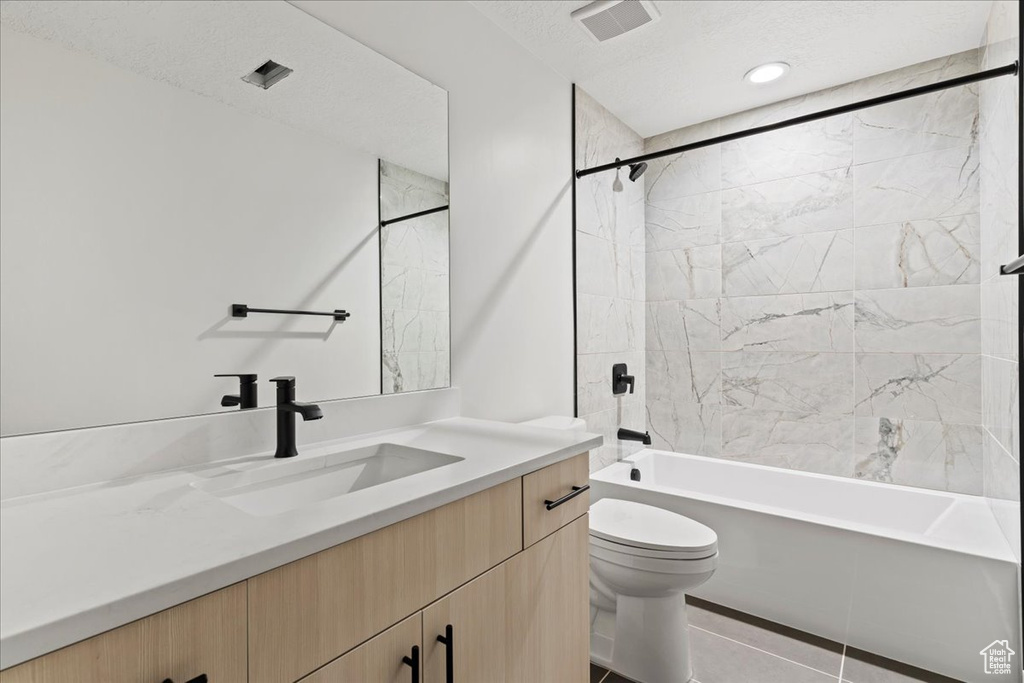 Full bathroom featuring tiled shower / bath, toilet, tile flooring, and oversized vanity