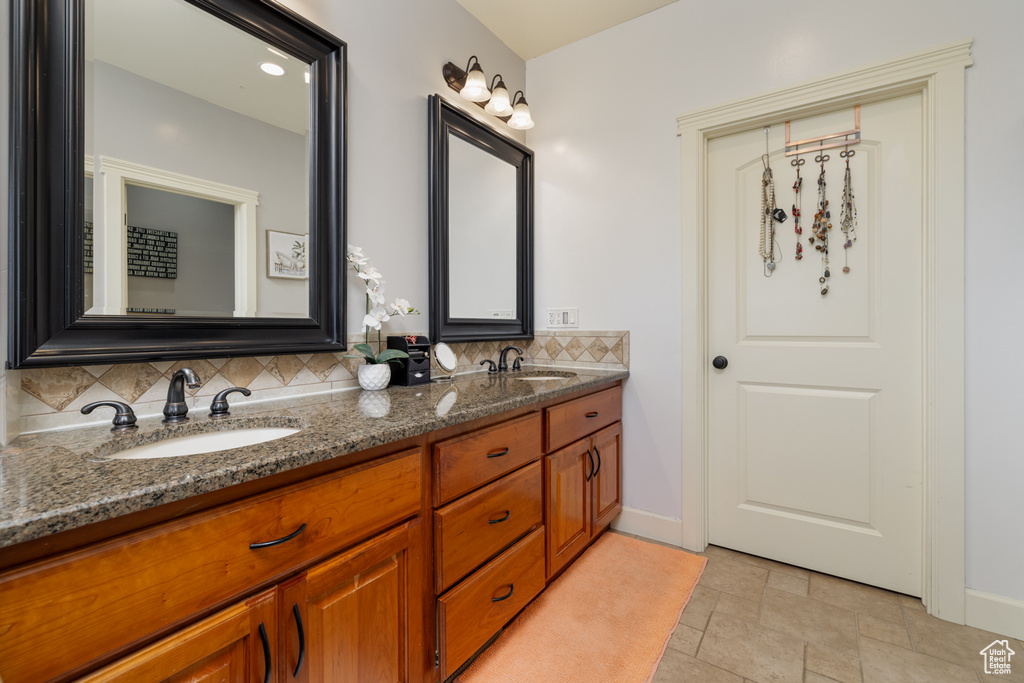 Bathroom featuring tasteful backsplash, dual bowl vanity, and tile flooring