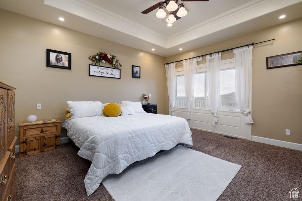 Carpeted bedroom featuring crown molding, ceiling fan, and a raised ceiling