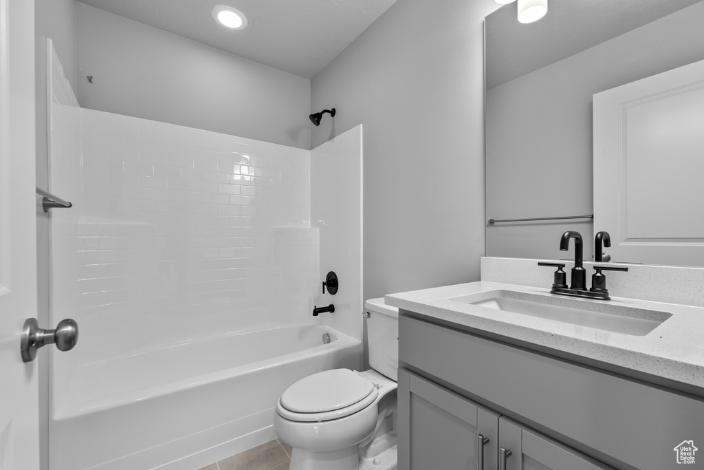 Full bathroom featuring toilet, tile flooring, vanity, and washtub / shower combination