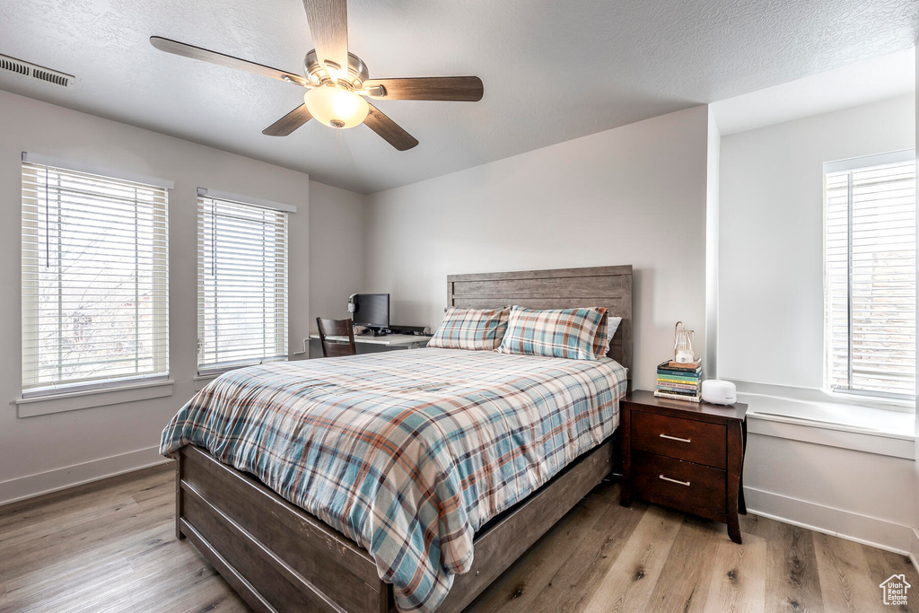 Bedroom featuring light hardwood / wood-style flooring, a textured ceiling, and ceiling fan