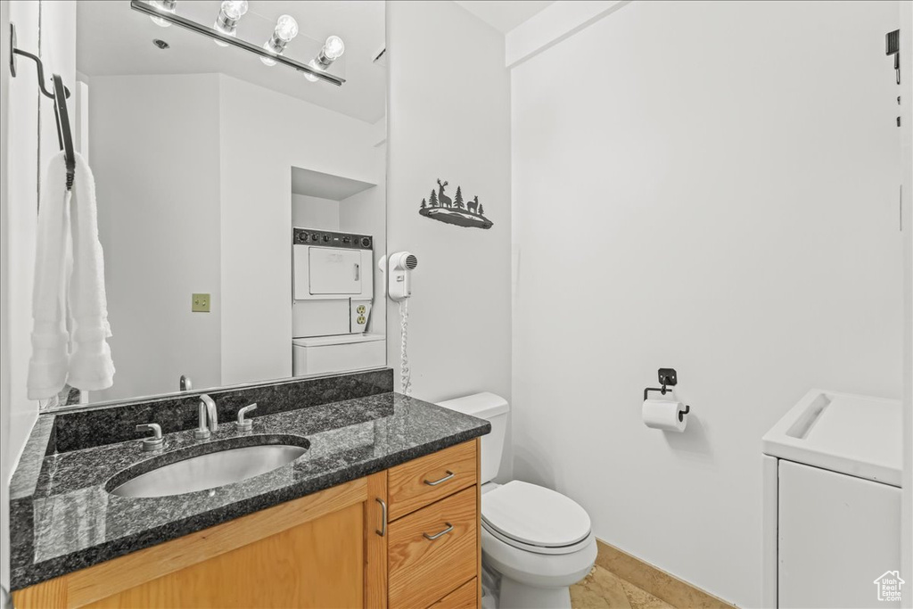 Bathroom featuring washer / dryer, tile flooring, vanity, and toilet