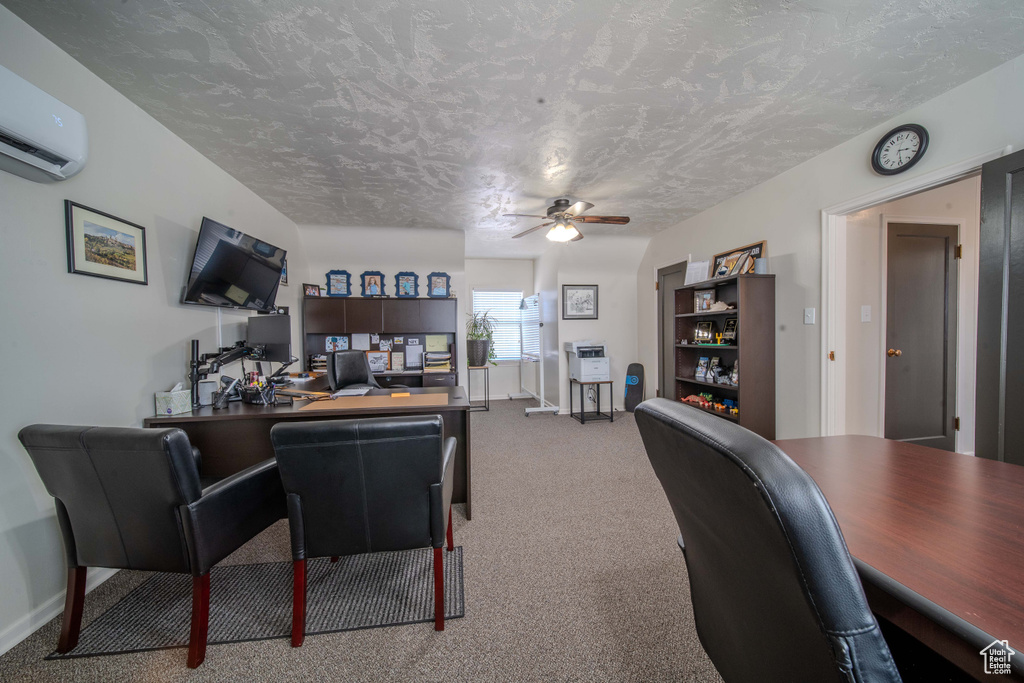 Carpeted office space with ceiling fan, a textured ceiling, and an AC wall unit