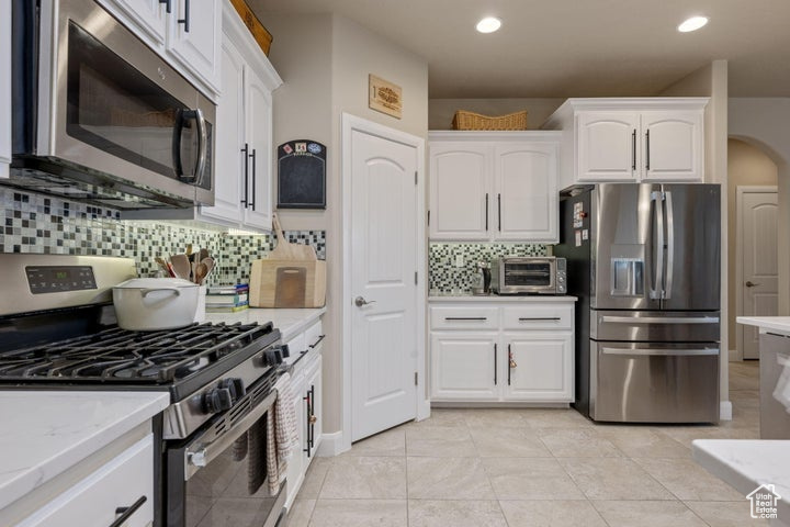 Kitchen featuring backsplash, white cabinets, and stainless steel appliances