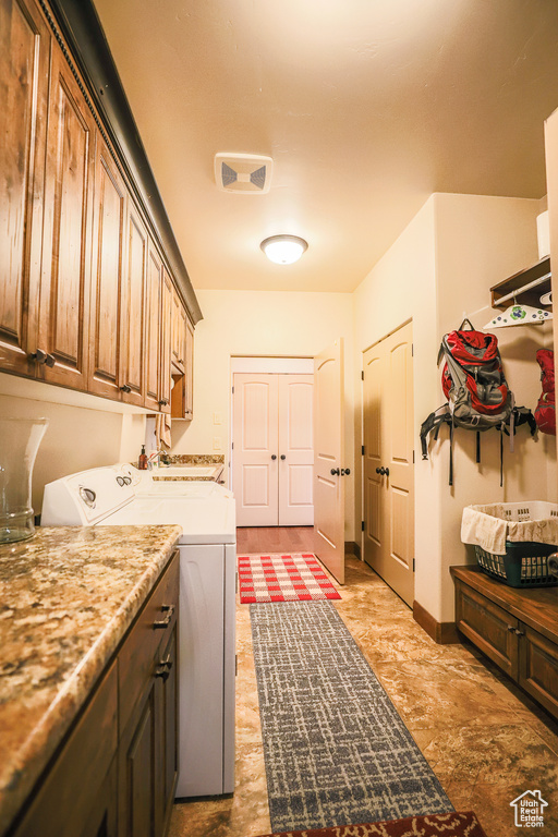 Laundry area featuring light tile floors, independent washer and dryer, and cabinets