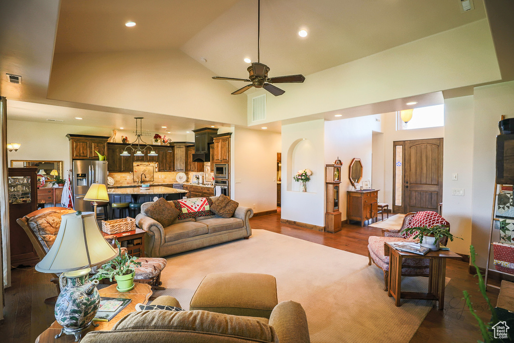 Living room featuring ceiling fan, high vaulted ceiling, and dark hardwood / wood-style floors