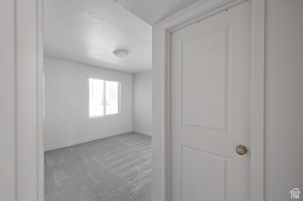 Empty room featuring a textured ceiling and carpet flooring