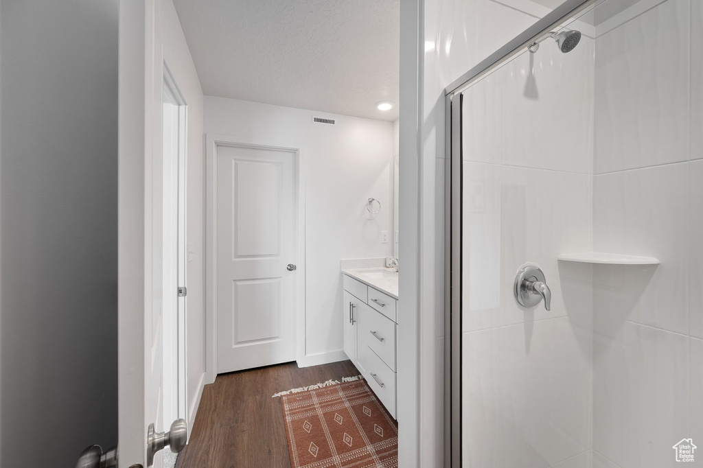 Bathroom with walk in shower, hardwood / wood-style floors, and vanity