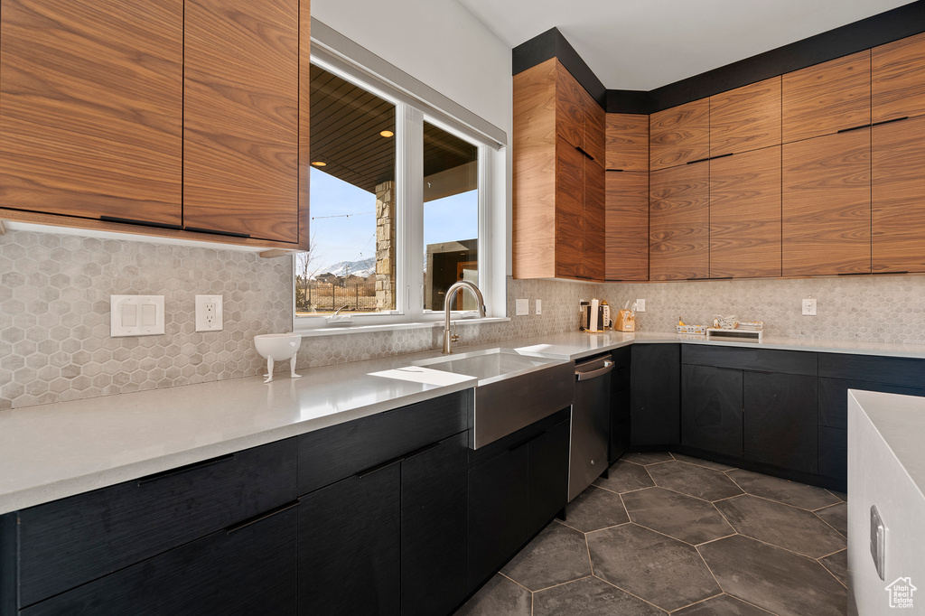 Kitchen featuring dark tile flooring, tasteful backsplash, sink, and dishwasher