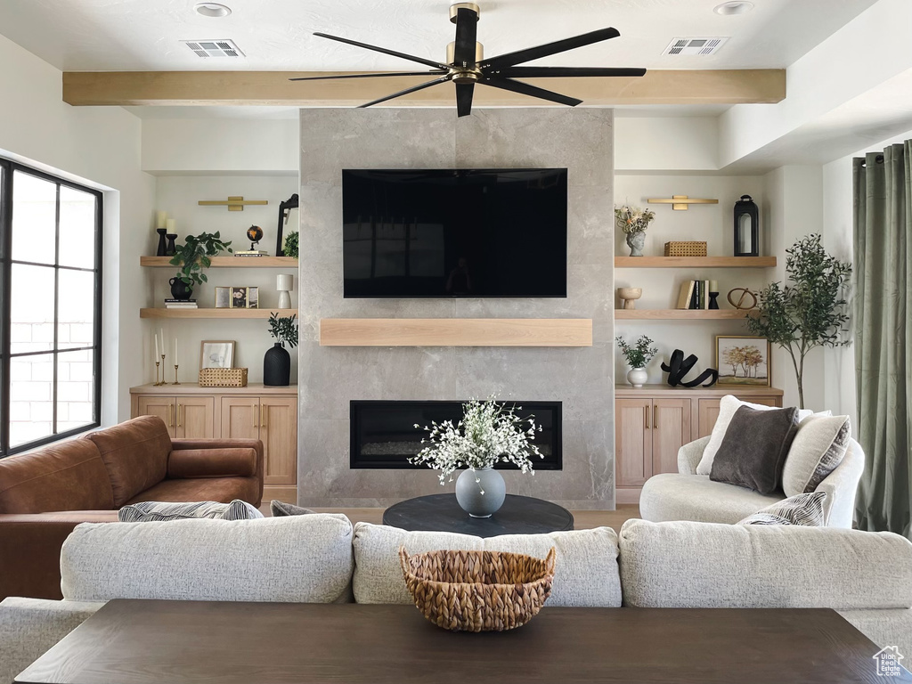Living room with built in shelves, a large fireplace, and ceiling fan