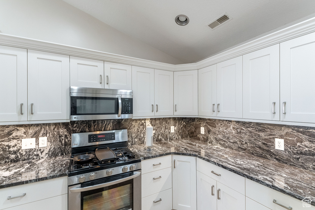 Kitchen featuring appliances with stainless steel finishes, white cabinets, and tasteful backsplash