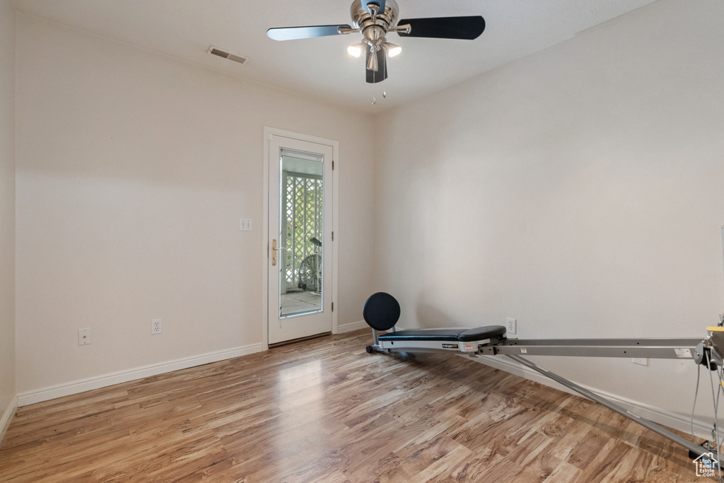 Workout area with light wood-type flooring and ceiling fan