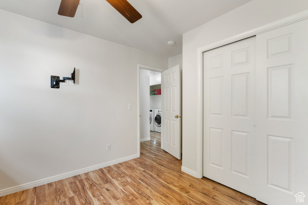 Unfurnished bedroom with a closet, ceiling fan, washing machine and clothes dryer, and light hardwood / wood-style floors