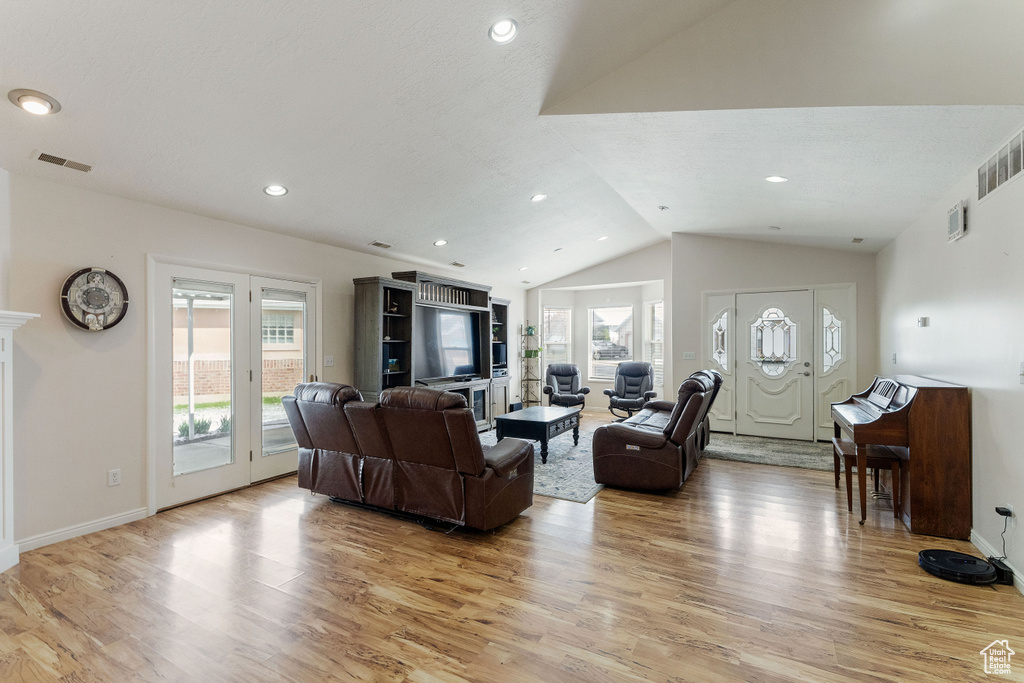 Living room with light hardwood / wood-style floors and lofted ceiling