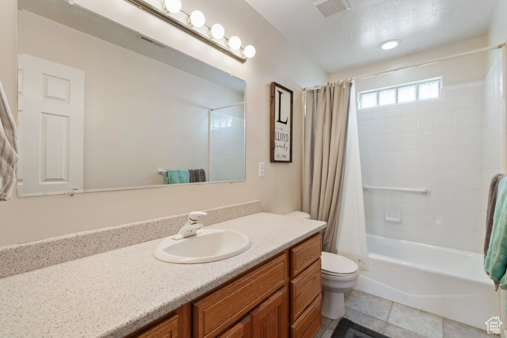 Full bathroom featuring large vanity, shower / tub combo with curtain, toilet, and tile floors