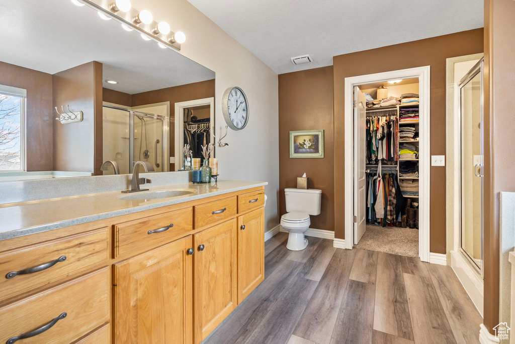 Bathroom featuring toilet, hardwood / wood-style floors, walk in shower, and vanity