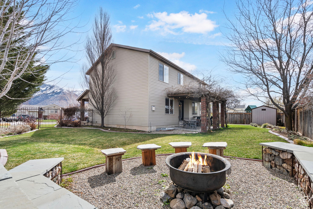 Back of property with a patio area, a mountain view, a fire pit, and a yard
