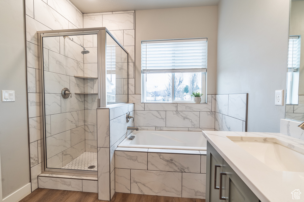 Bathroom featuring hardwood / wood-style floors, vanity, and plus walk in shower