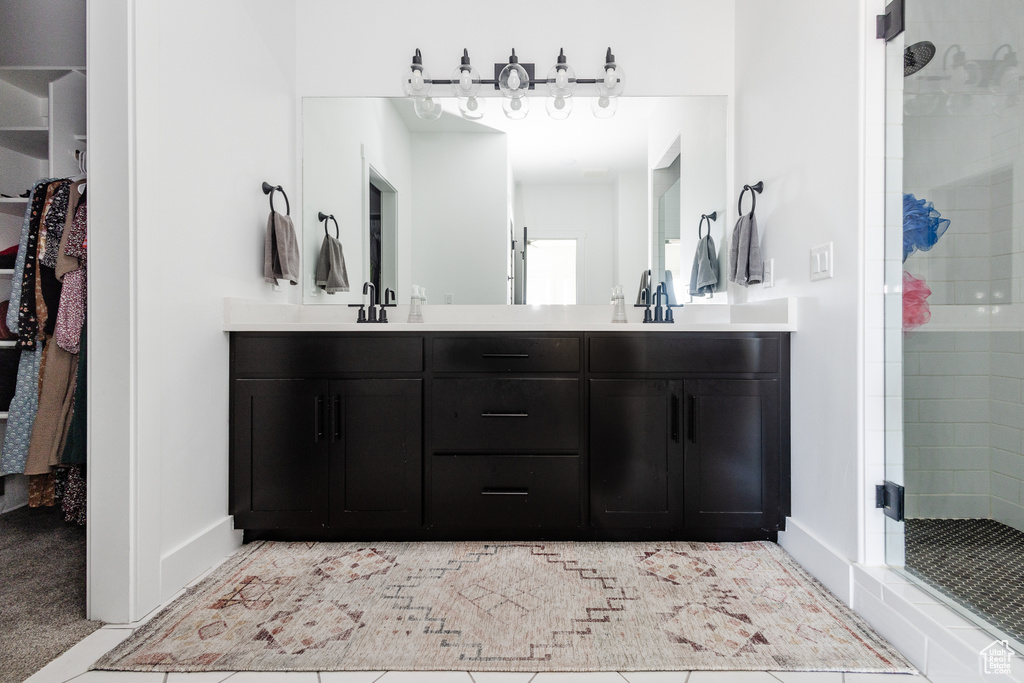 Bathroom featuring walk in shower, vanity with extensive cabinet space, and double sink