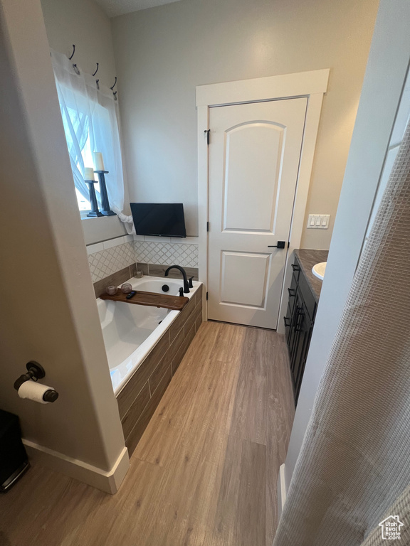 Bathroom with hardwood / wood-style flooring, vanity, and tiled tub