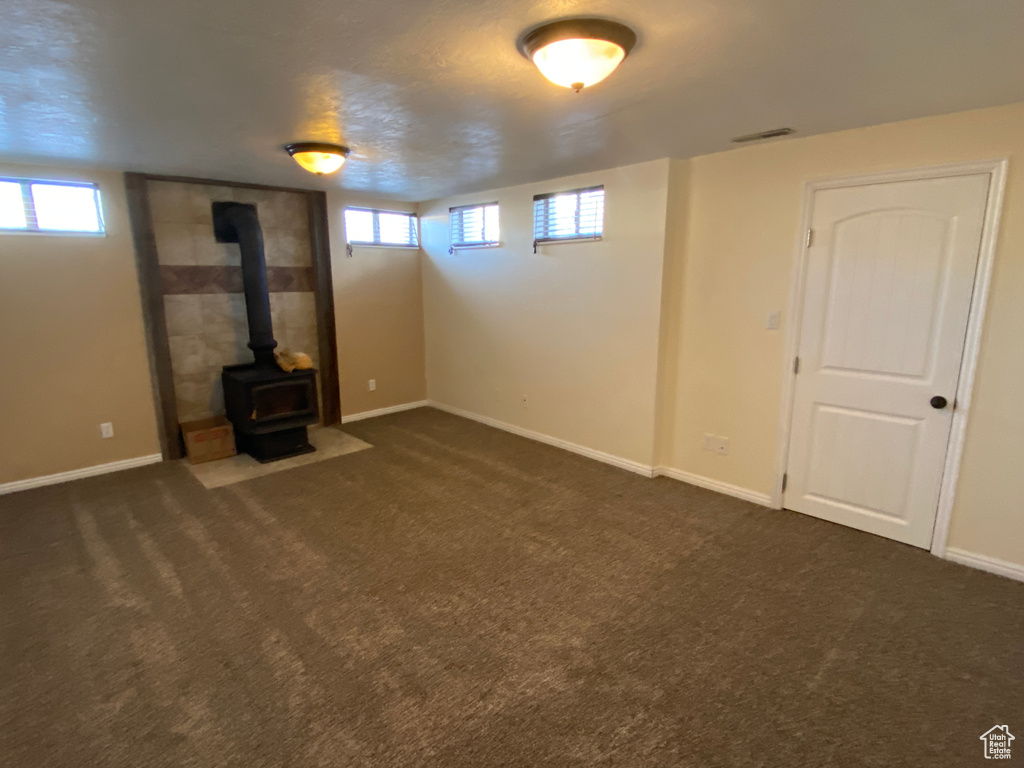 Basement with dark colored carpet and a wood stove