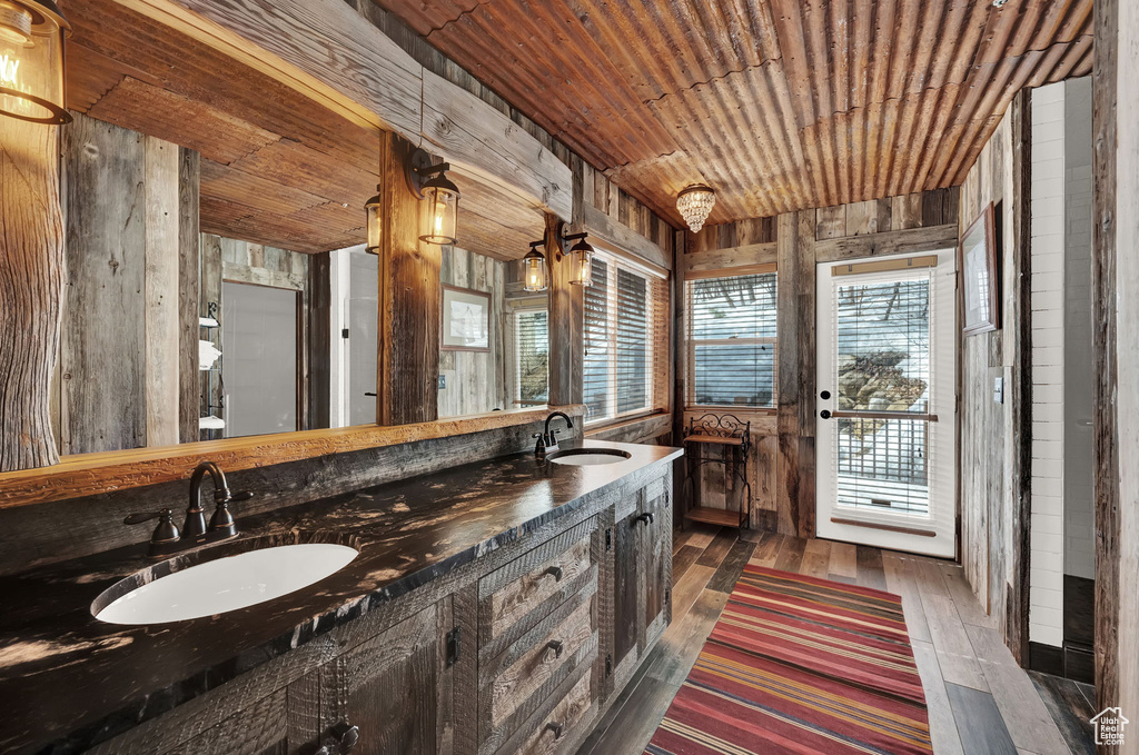 Bathroom with wood-type flooring, wooden ceiling, wooden walls, vanity with extensive cabinet space, and plenty of natural light