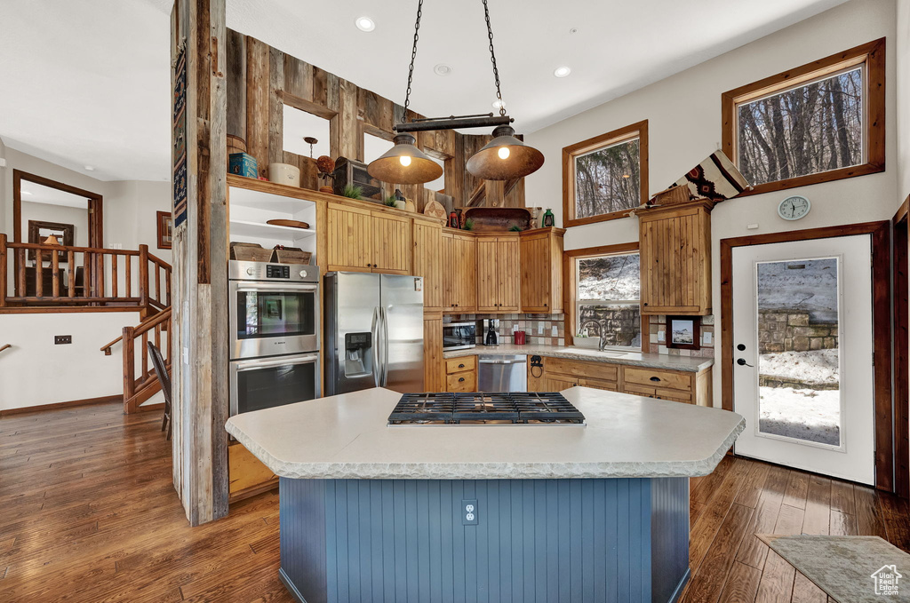 Kitchen with a center island, appliances with stainless steel finishes, sink, tasteful backsplash, and dark wood-type flooring