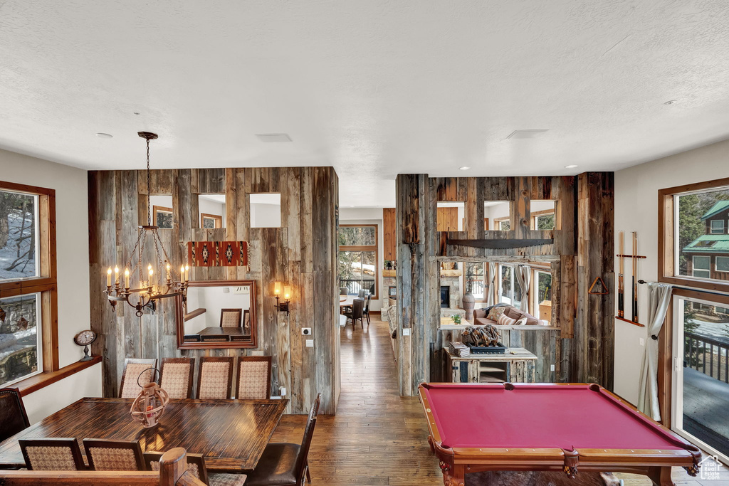 Recreation room with billiards, a notable chandelier, wooden walls, and dark wood-type flooring