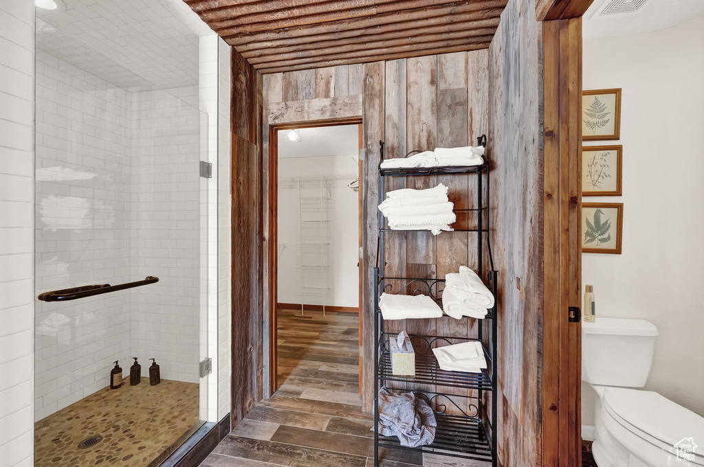 Bathroom featuring toilet, a shower with shower door, and wood-type flooring