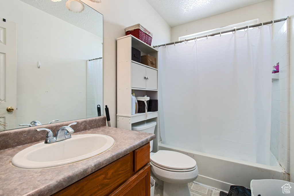 Full bathroom featuring shower / tub combo, tile flooring, vanity, a textured ceiling, and toilet