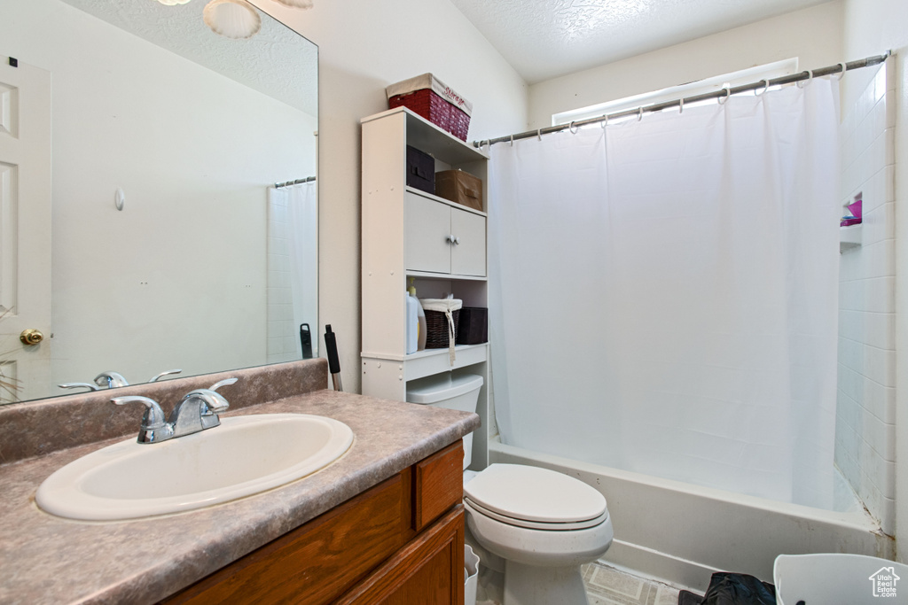 Full bathroom featuring vanity, a textured ceiling, shower / bath combination with curtain, tile floors, and toilet