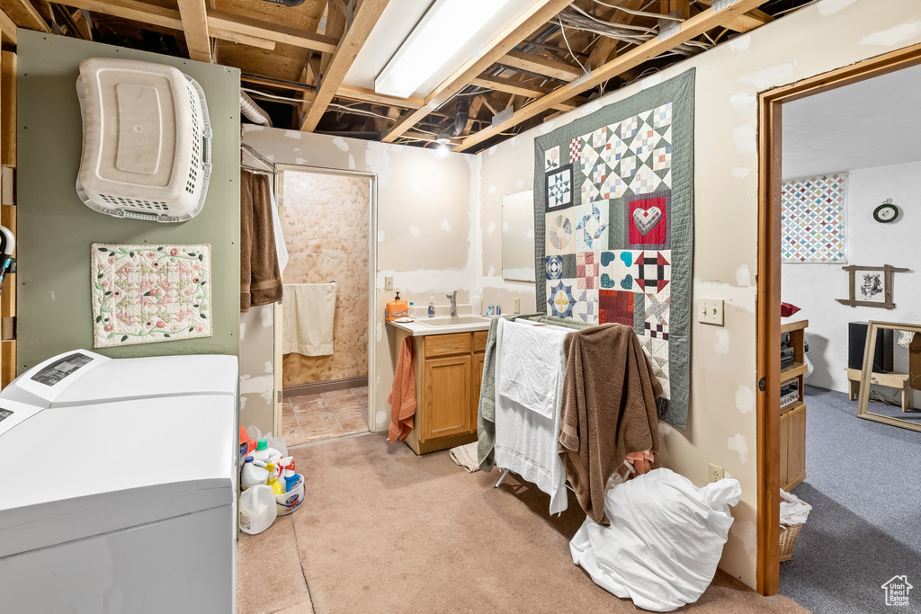 Basement featuring sink, washer and clothes dryer, and light carpet