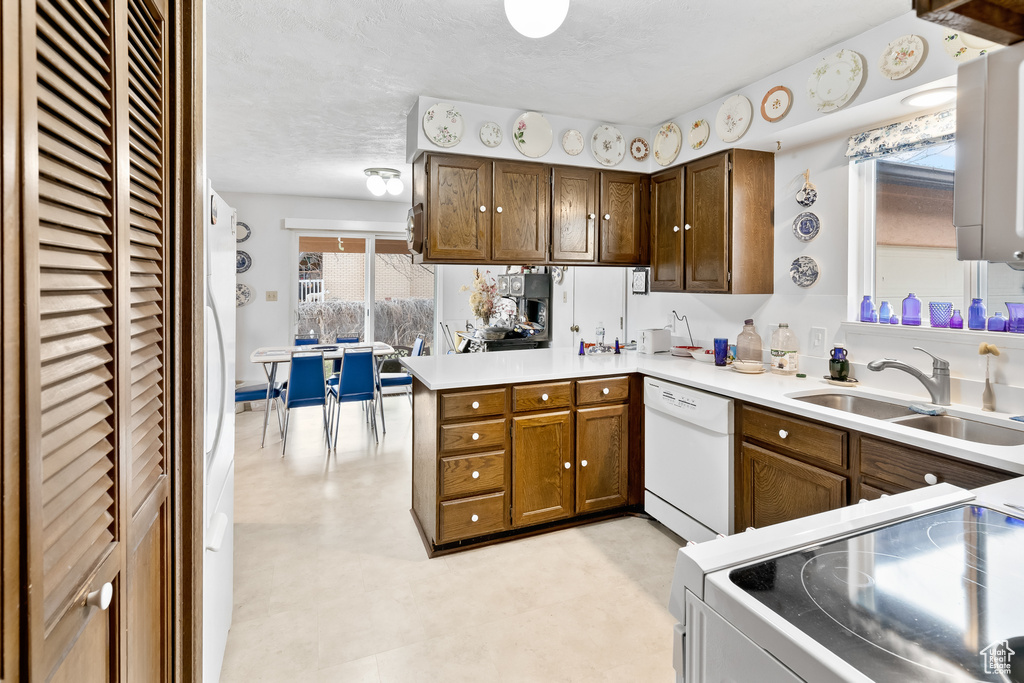 Kitchen featuring sink, white appliances, and kitchen peninsula