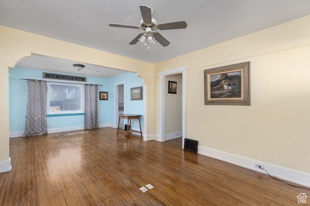 Unfurnished room featuring dark wood-type flooring and ceiling fan