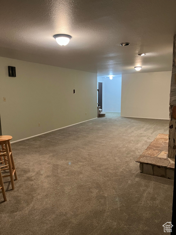 Basement with a textured ceiling and light colored carpet
