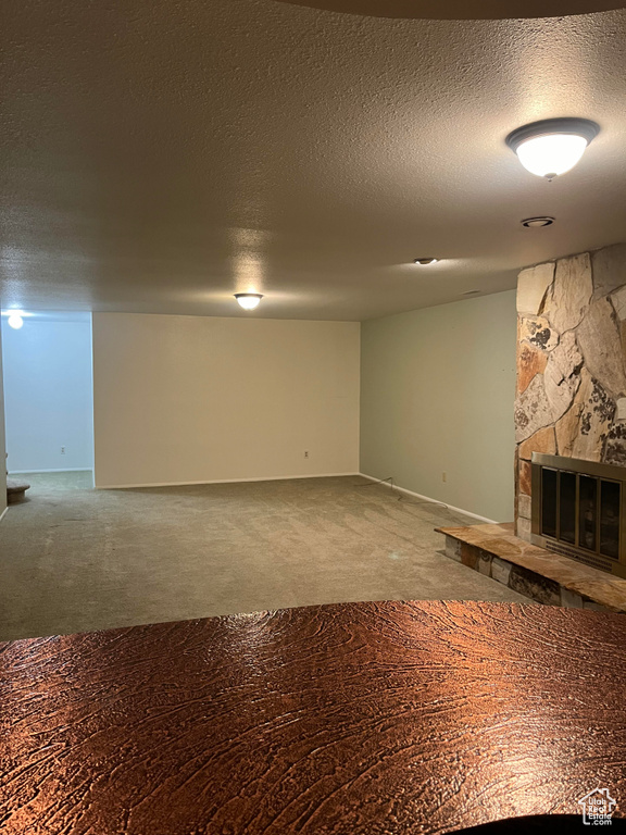 Basement featuring a fireplace, a textured ceiling, and carpet
