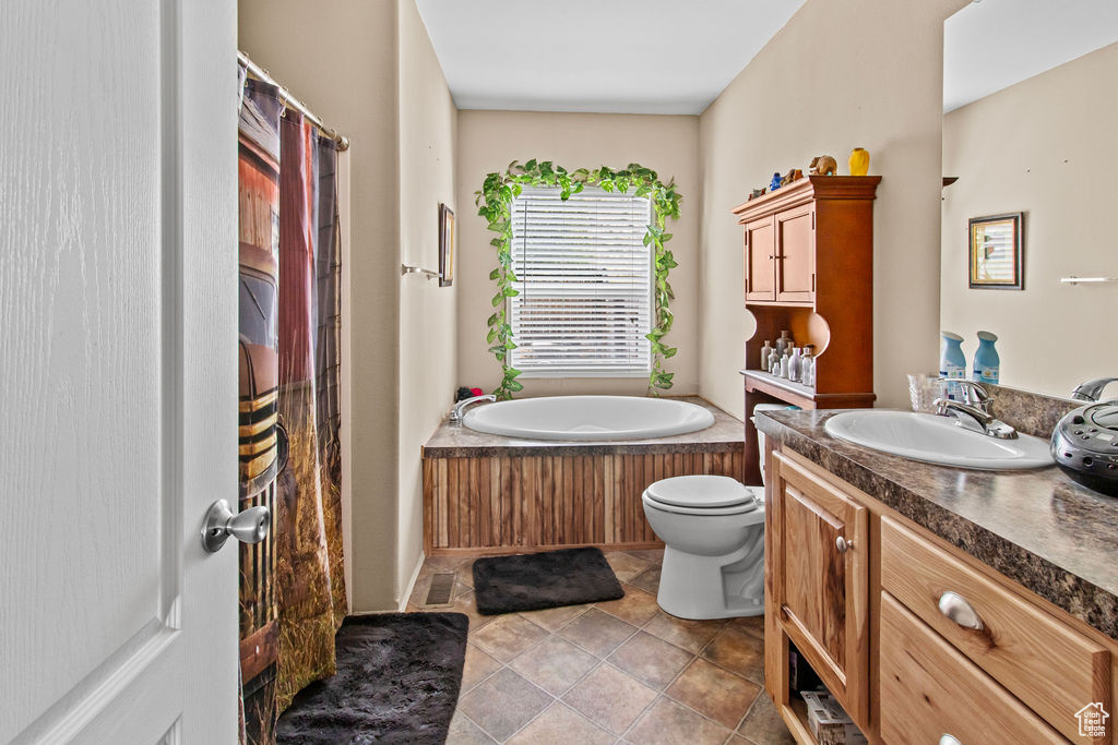 Bathroom with tile floors, a washtub, vanity, and toilet