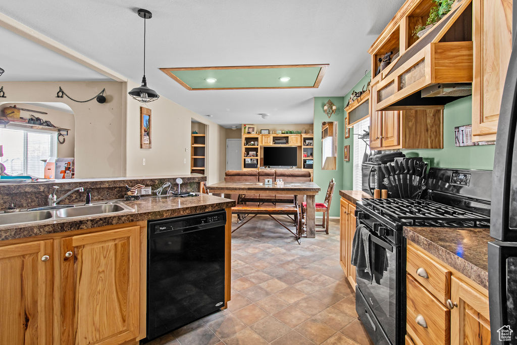 Kitchen with sink, light tile flooring, black appliances, and decorative light fixtures