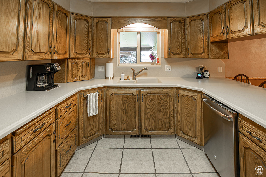 Kitchen with stainless steel dishwasher, sink, and light tile floors