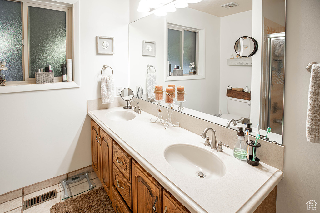 Bathroom featuring toilet, tile flooring, oversized vanity, and dual sinks