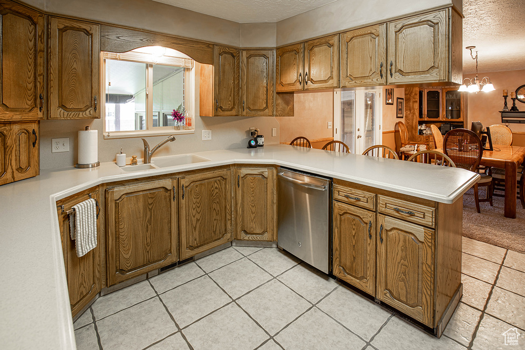 Kitchen featuring sink, decorative light fixtures, a chandelier, stainless steel dishwasher, and light tile floors