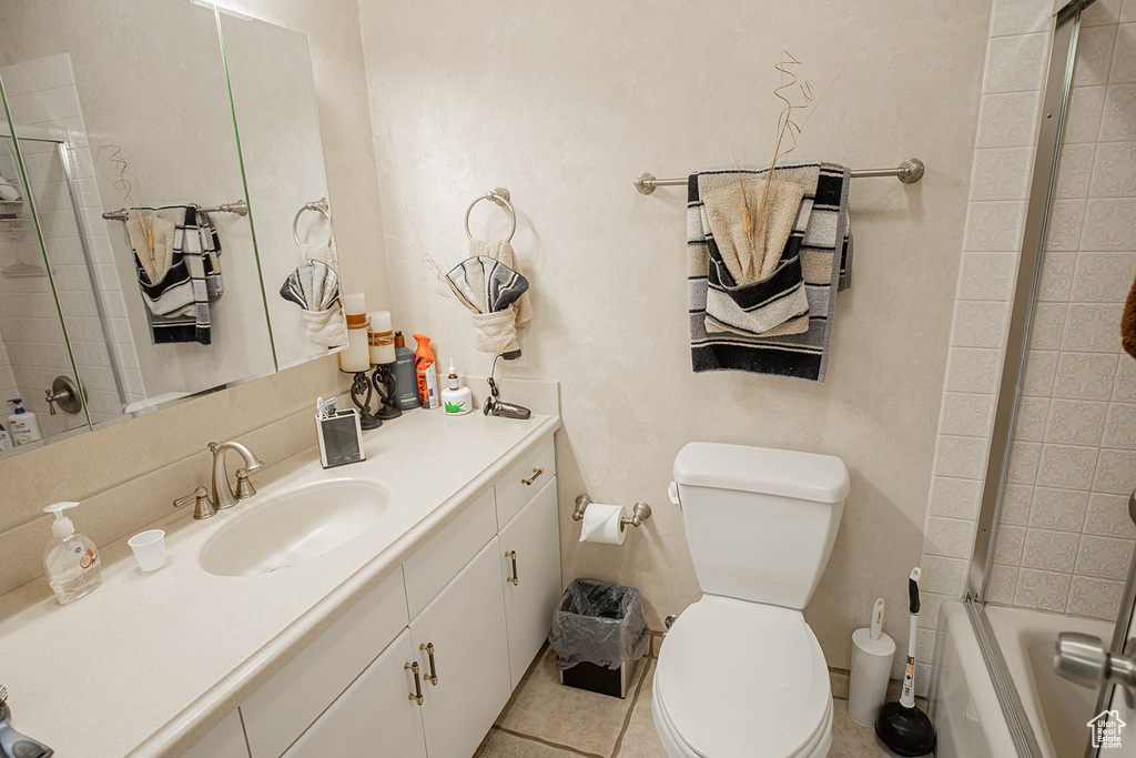 Full bathroom featuring toilet, tile flooring, bath / shower combo with glass door, and oversized vanity