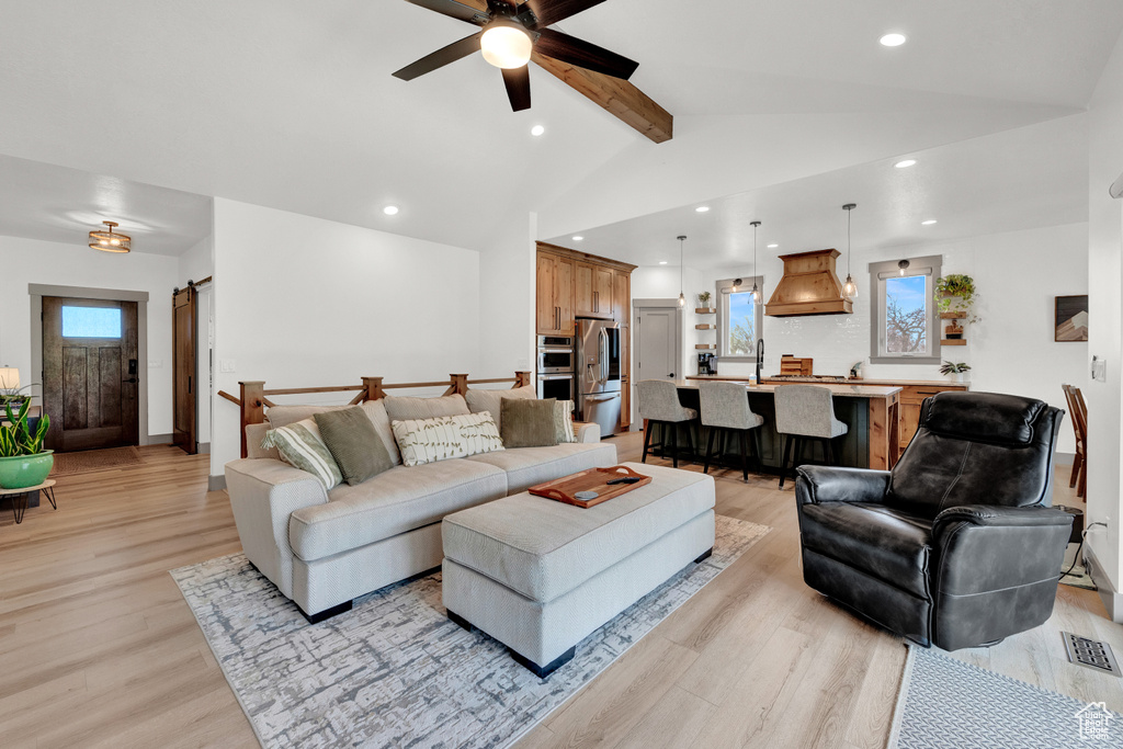 Living room featuring lofted ceiling with beams, sink, ceiling fan, and light hardwood / wood-style floors