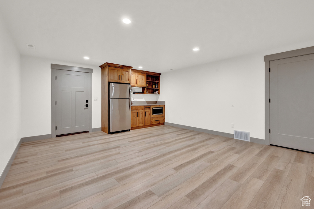 Interior space with light hardwood / wood-style floors and stainless steel fridge