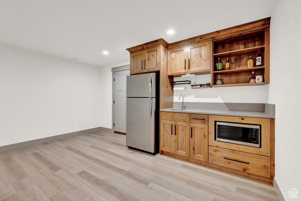 Kitchen with stainless steel appliances, sink, and light hardwood / wood-style floors