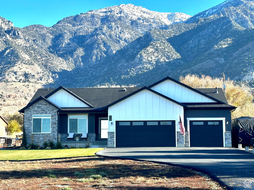 View of front facade with a mountain view, a front yard, and a garage