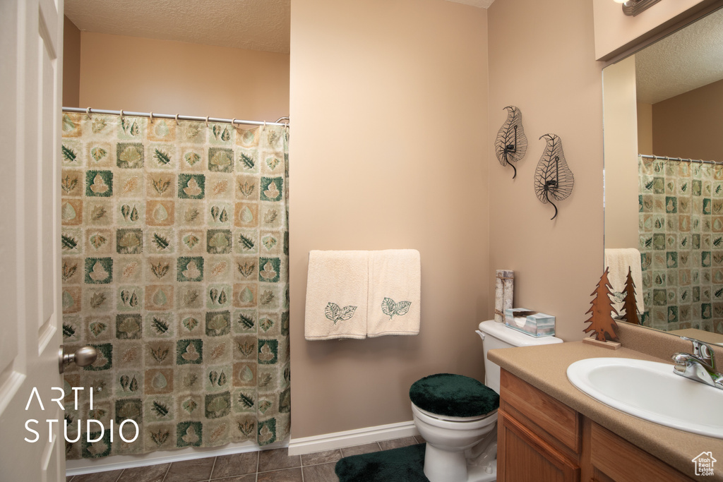 Bathroom with vanity, toilet, a textured ceiling, and tile floors